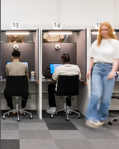 Examencabines bij het CBR: kandidaten maken het theorie-examen achter een computer
